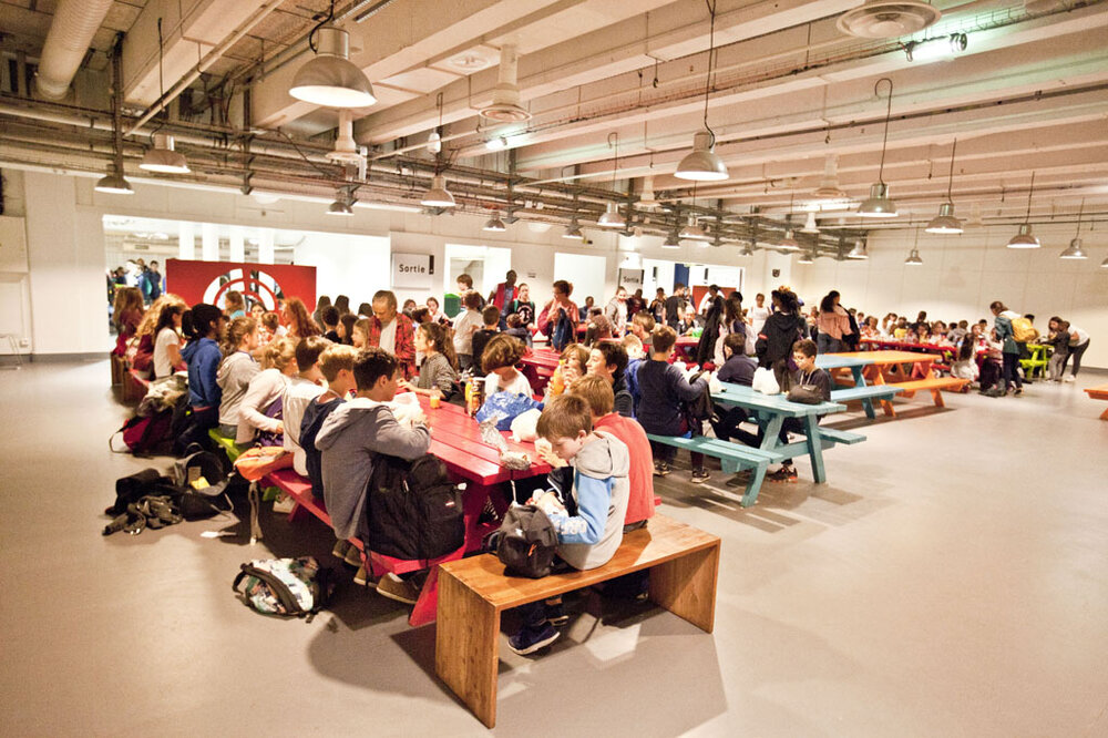 Groupes d'enfant qui mangent sur des tables de pique nique au niveau -1 du musée.